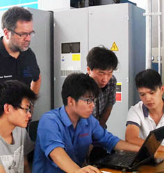 4 junge Chinesen und ein deutscher Ausbilder gucken auf ein Laptop