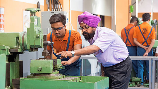 Indischer Ausbilder und Auszubildender arbeiten an einer Fräsmaschine