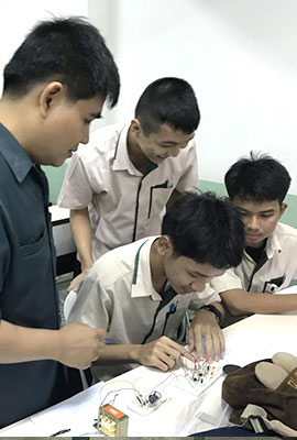 thailändischer Ausbilder beobachtet thailändische Auszubildende, die im Bereich Elektrik arbeiten