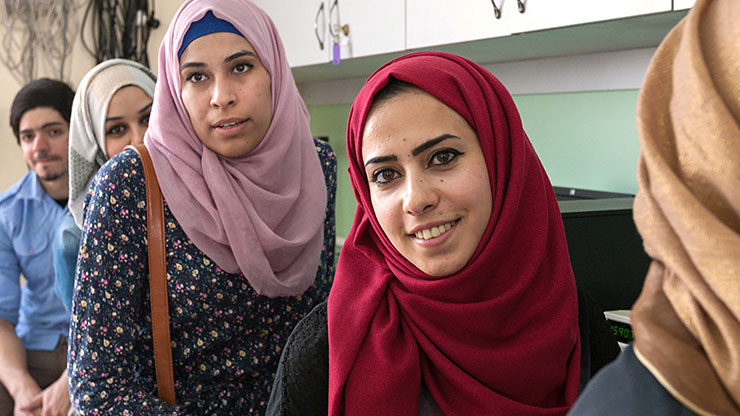 mehrere junge Frauen aus dem arabischen Raum schauen Richtung Kamera offenbar während einer Schulung