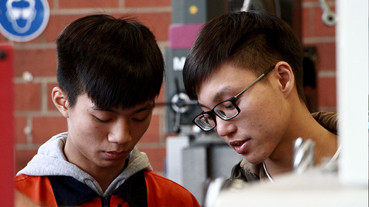 zwei mutmaßlich chinesische junge Männer in Arbeitskleidung