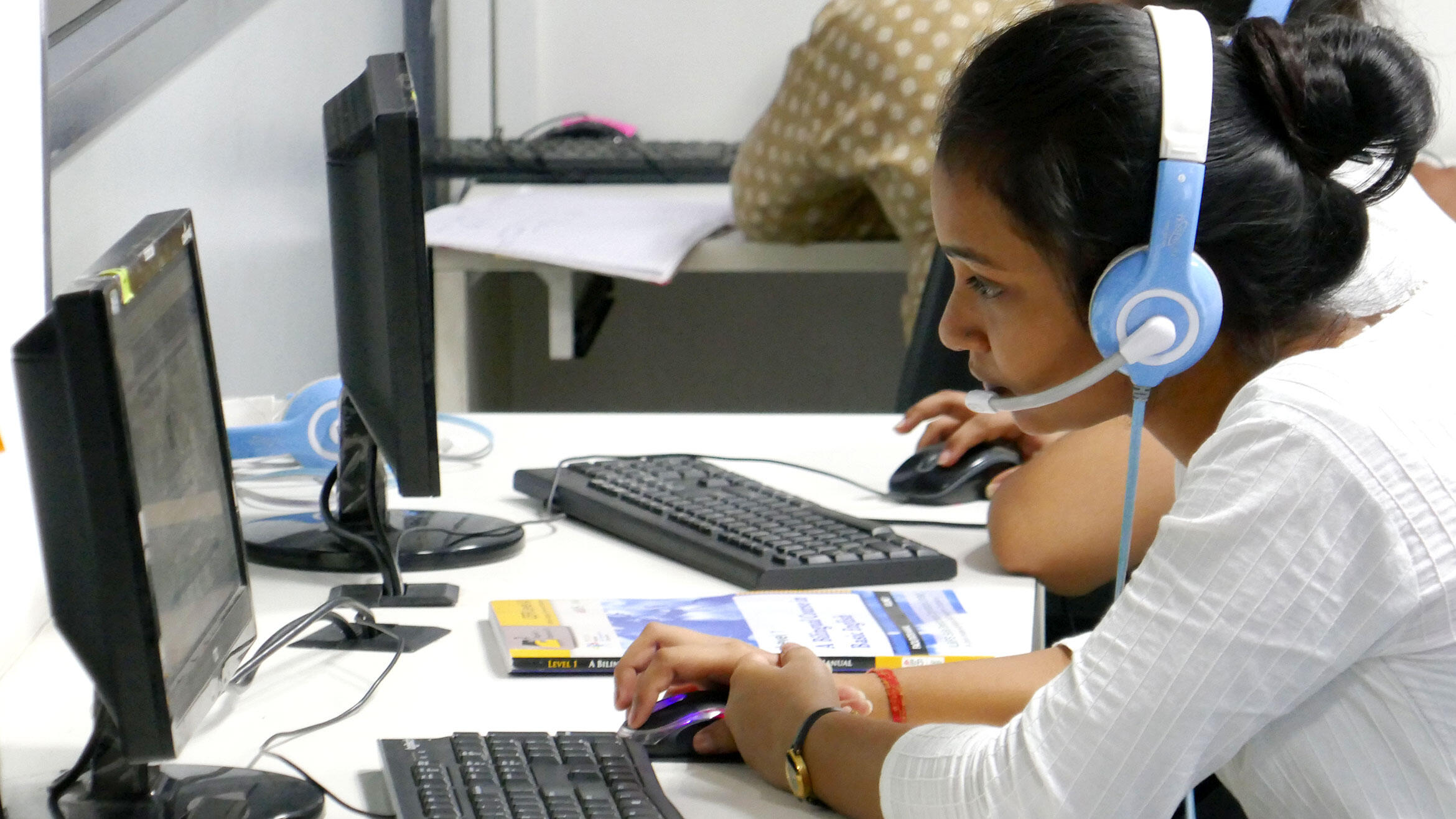 young Indian woman with headphones sitting at the computer