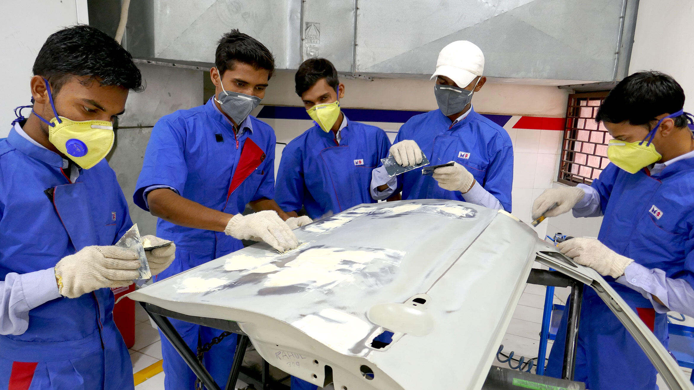 five young Indians are practicing spatula on a car door