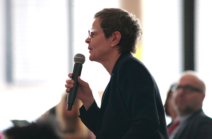 close-up of a participant asking a question to the speakers on the podium