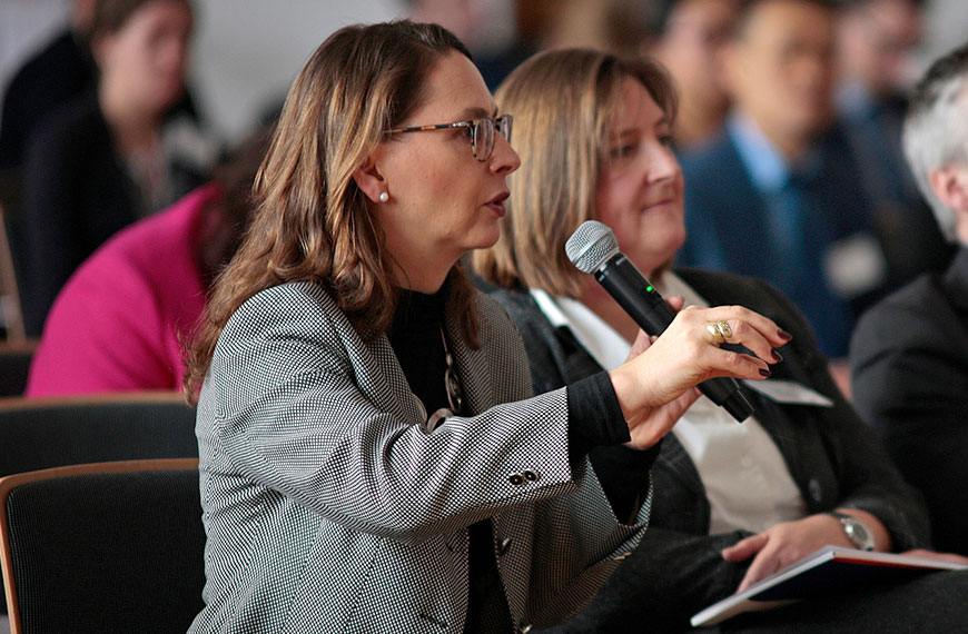 participant asking a question to speakers on the podium