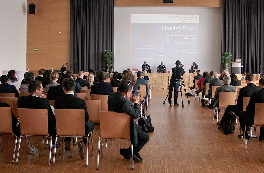 View into the well filled conference room from the audience to the speakers