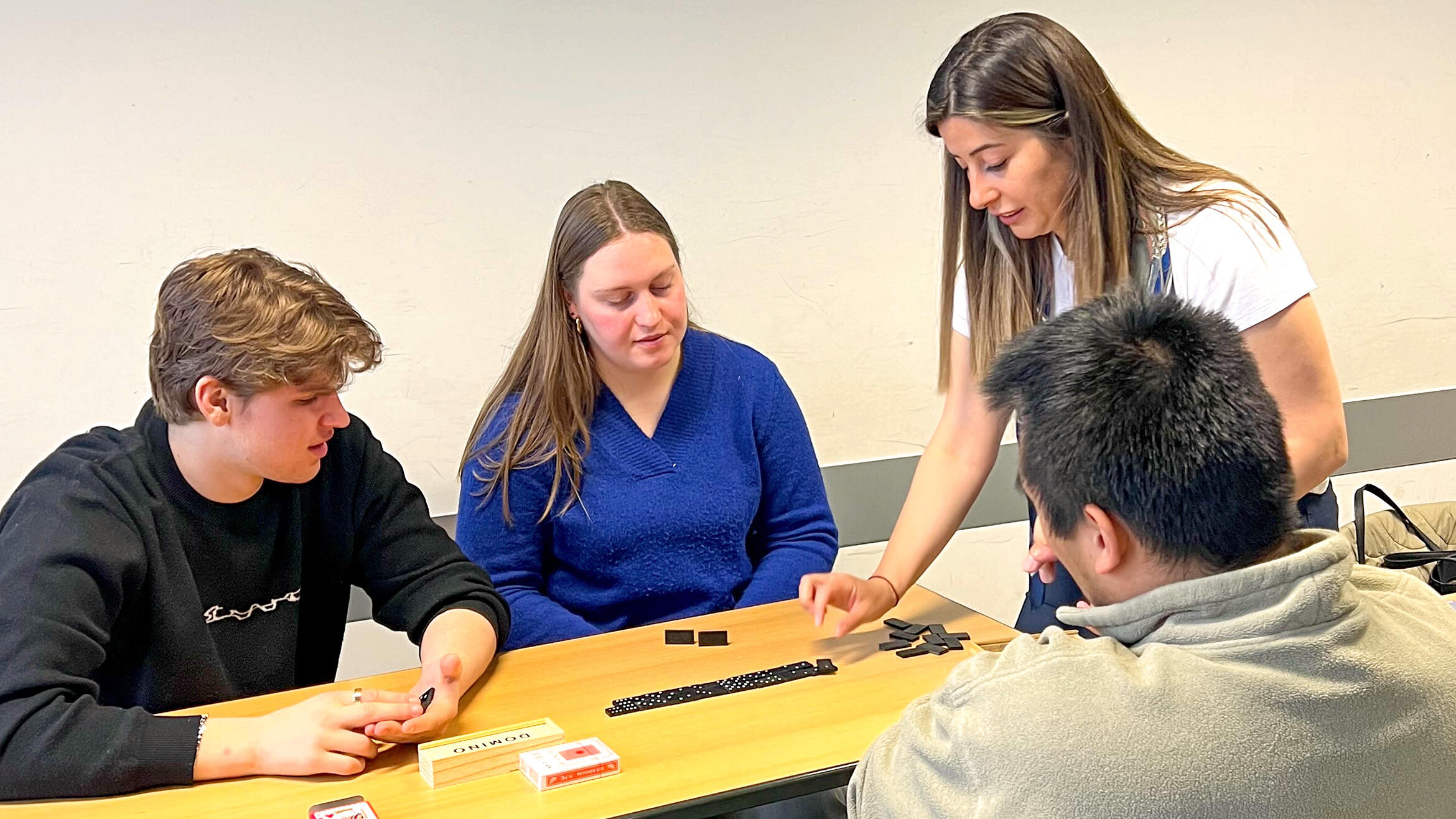 four people sitting around a table using dominoes