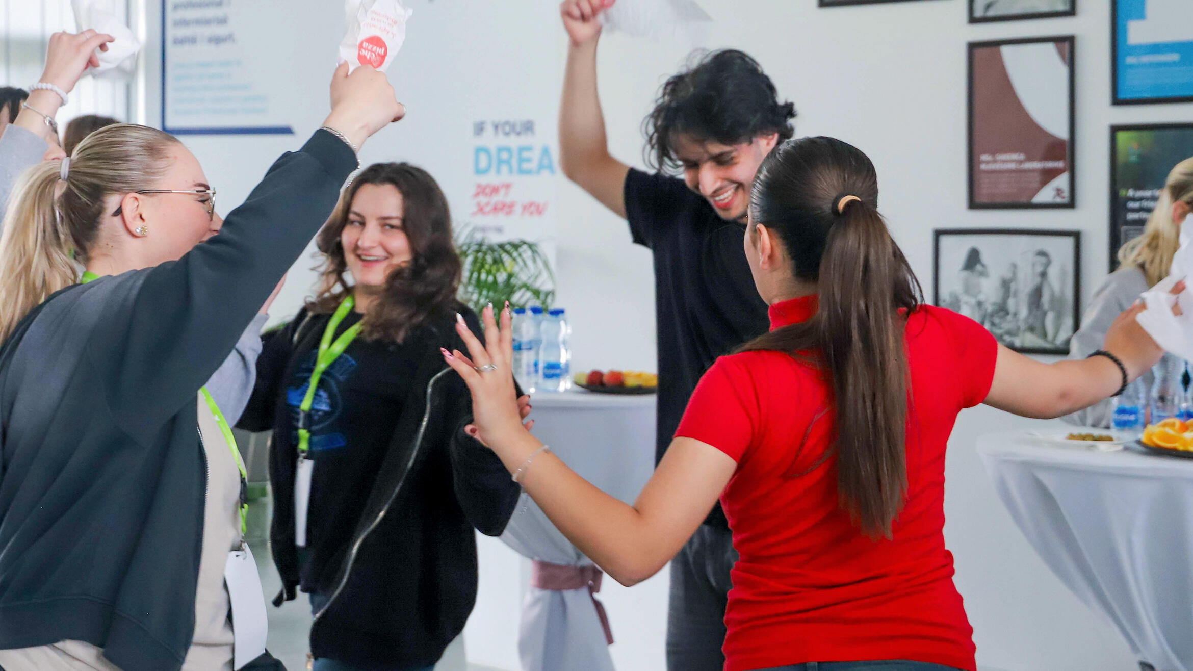 four young people standing in a circle with their arms raised
