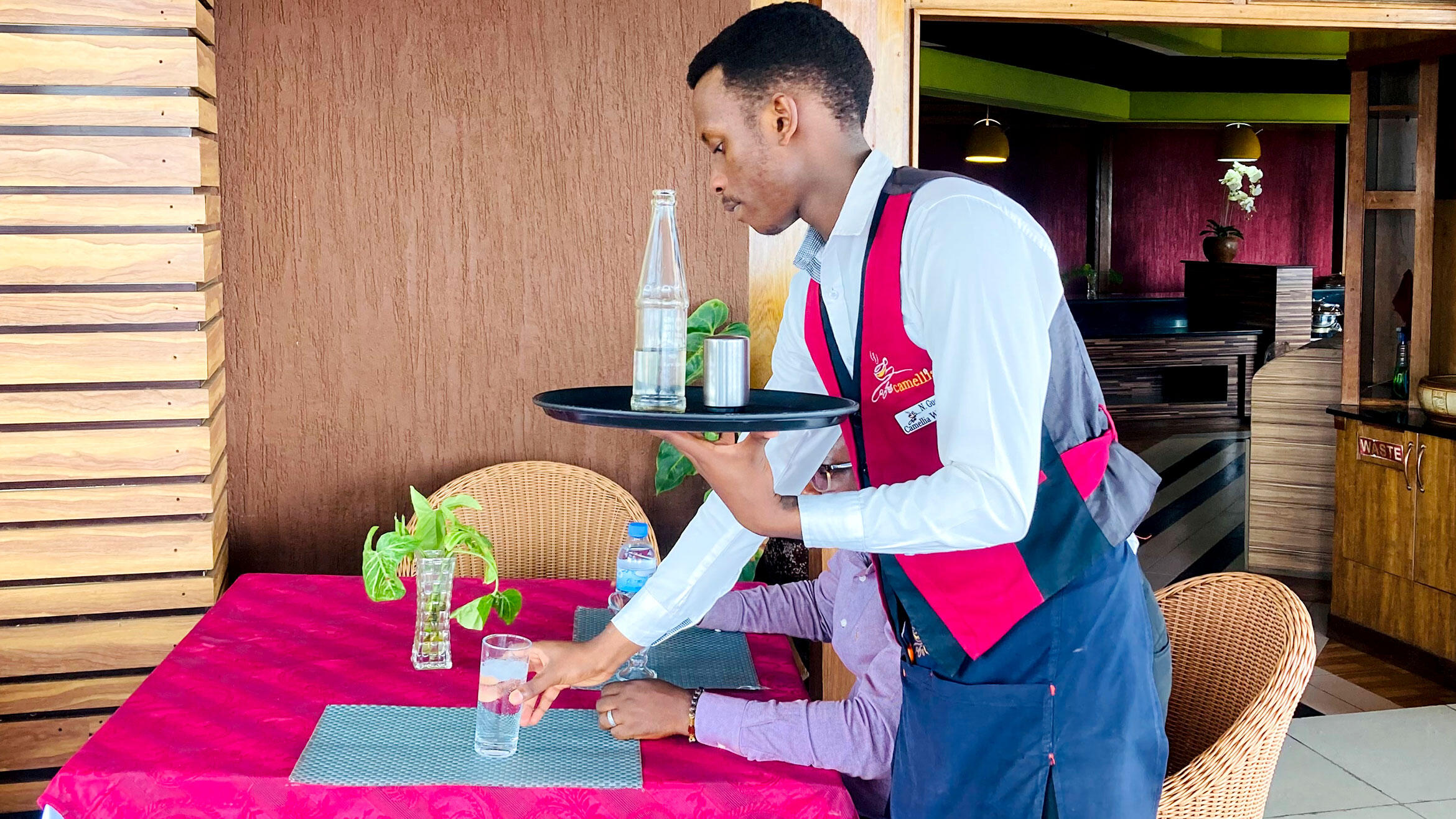 waiter, presumably in training, serves a guest