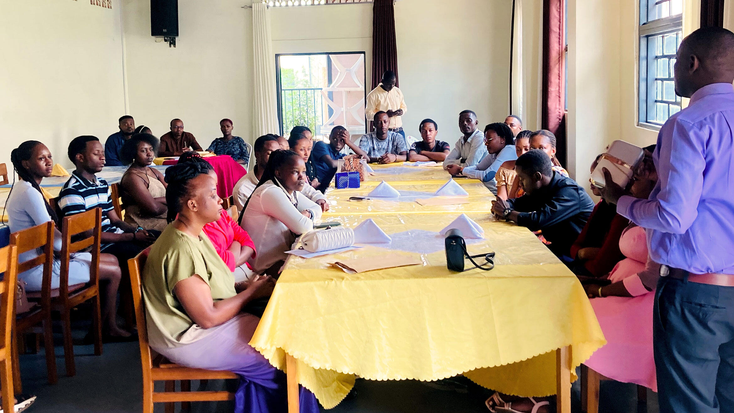 scene of a classroom lesson. Trainees are sitting at round tables and the teacher is in the foreground
