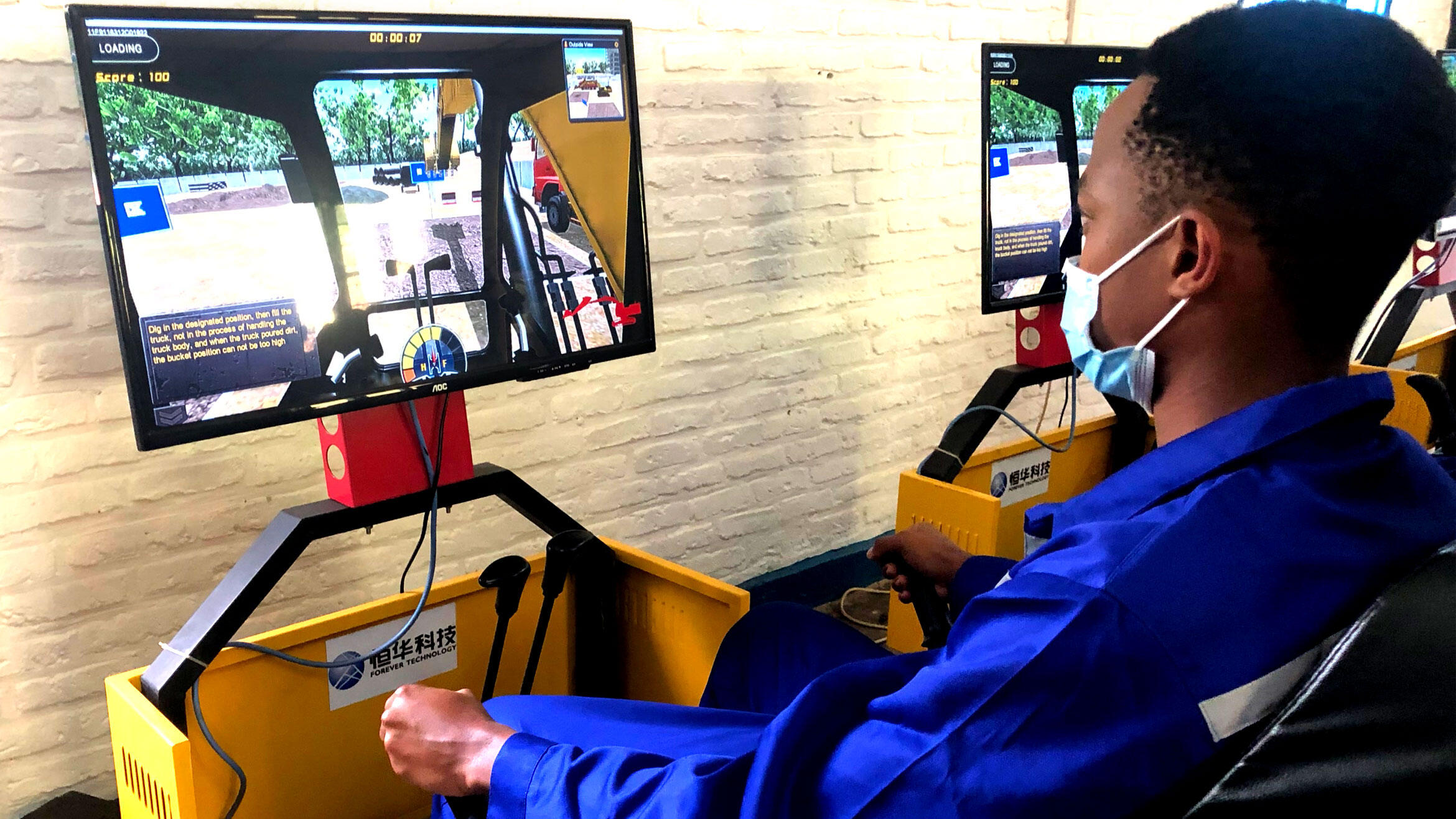 a man from Rwanda practices driving a construction machine on a simulator