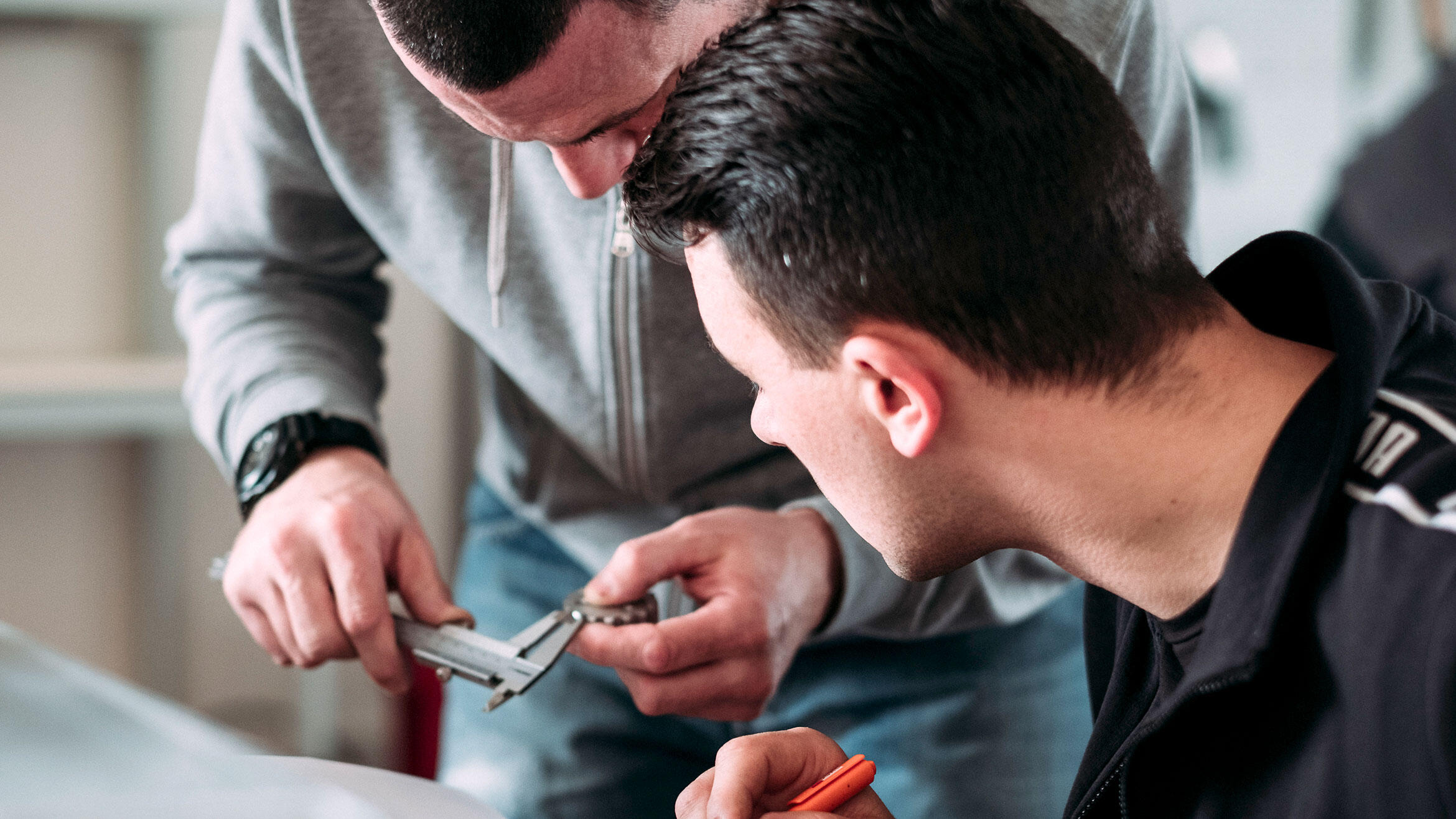 Close-up: young Serbian observing a person measuring an object