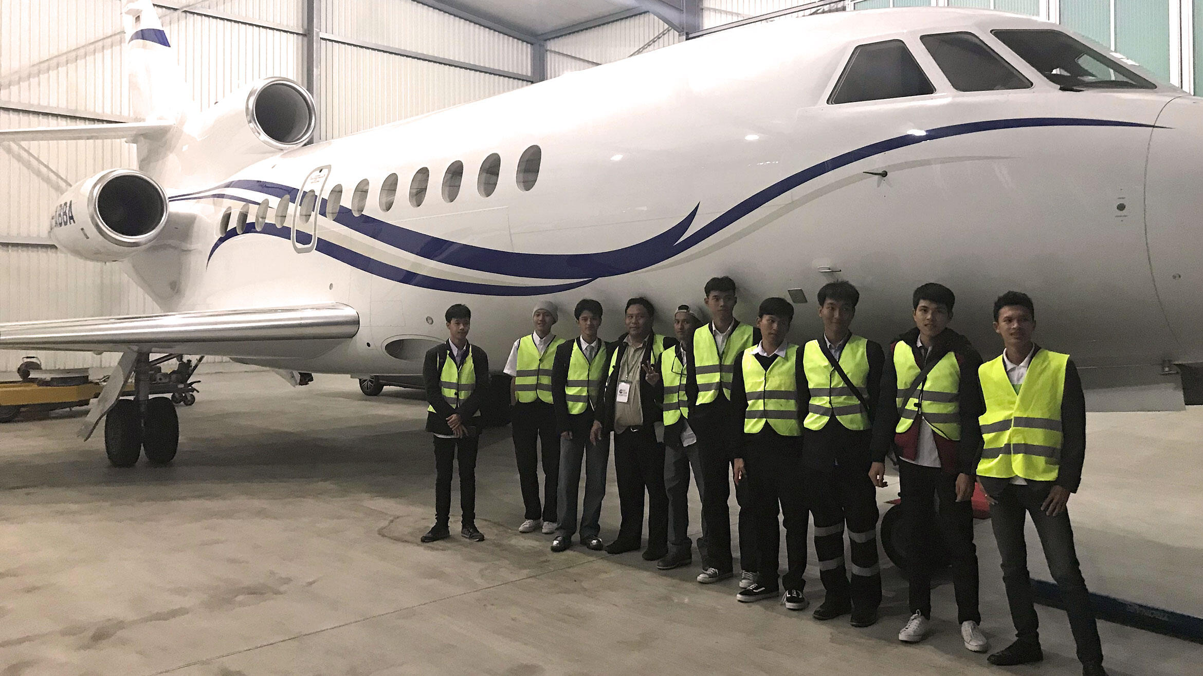 group of Thais stands in front of a passenger plane