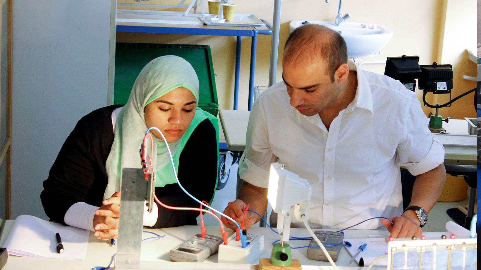 woman and man working on electrical system standing on a table