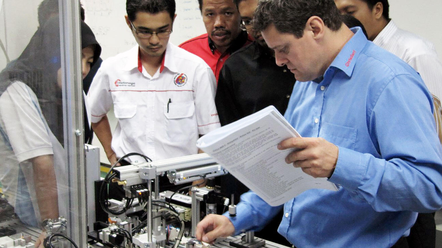 some people from Malysia working in a workshop