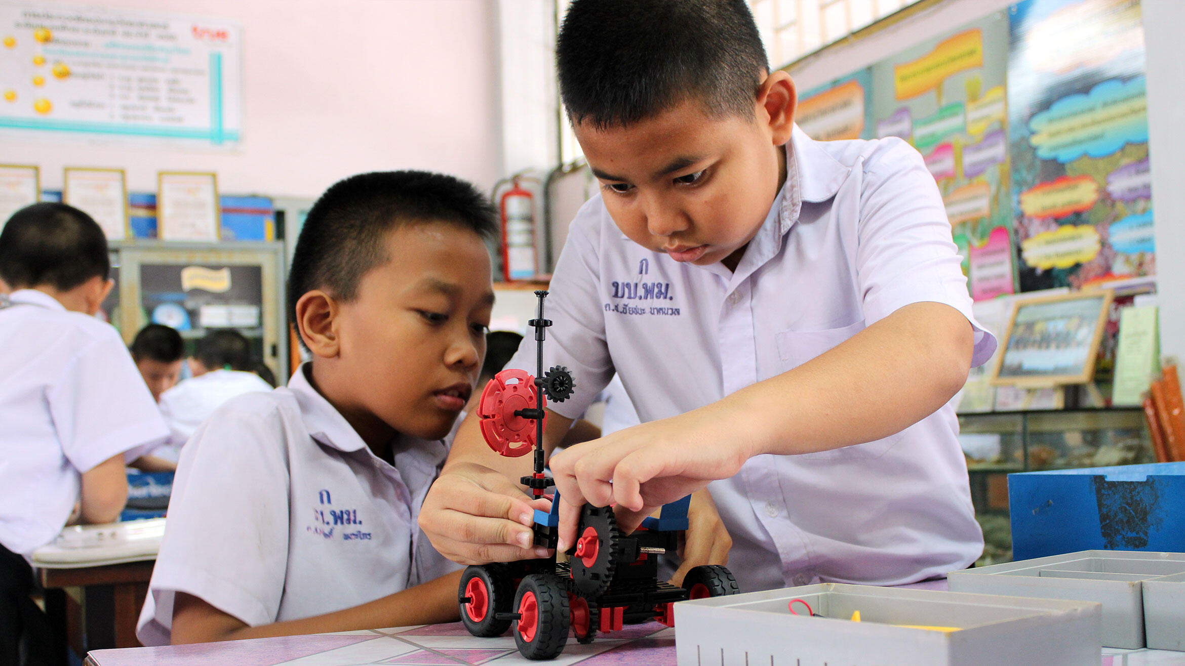 two Asian boys build a vehicle with technical game components