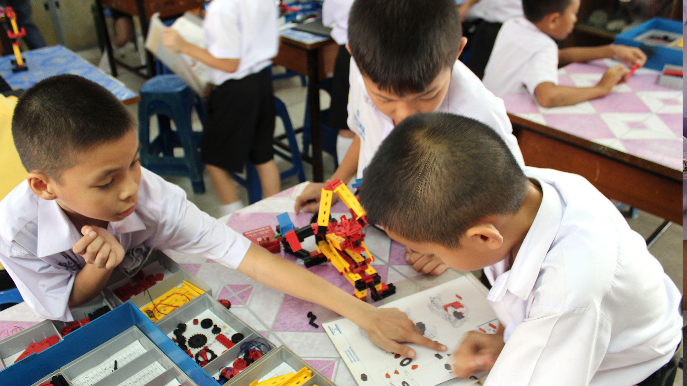 Asian kids ply with technical game pieces