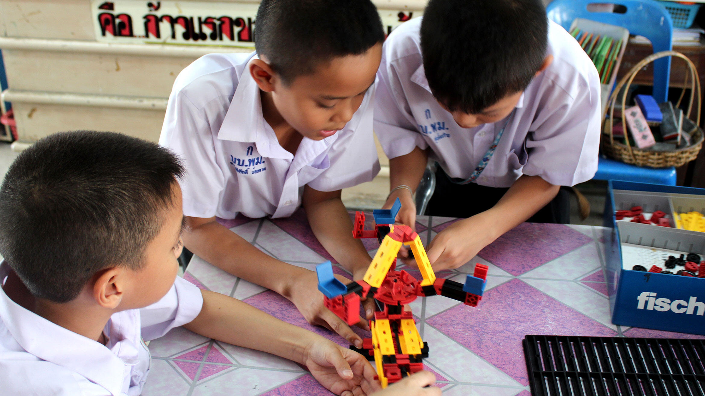 three Asian boys play with technical game pieces