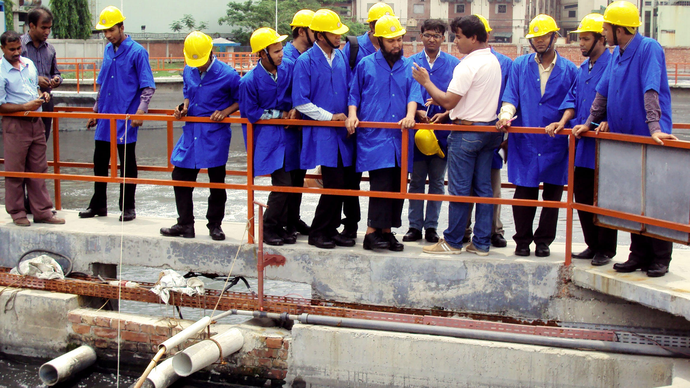 men in work clothes and protective helmets inspect a part of a sewage plant