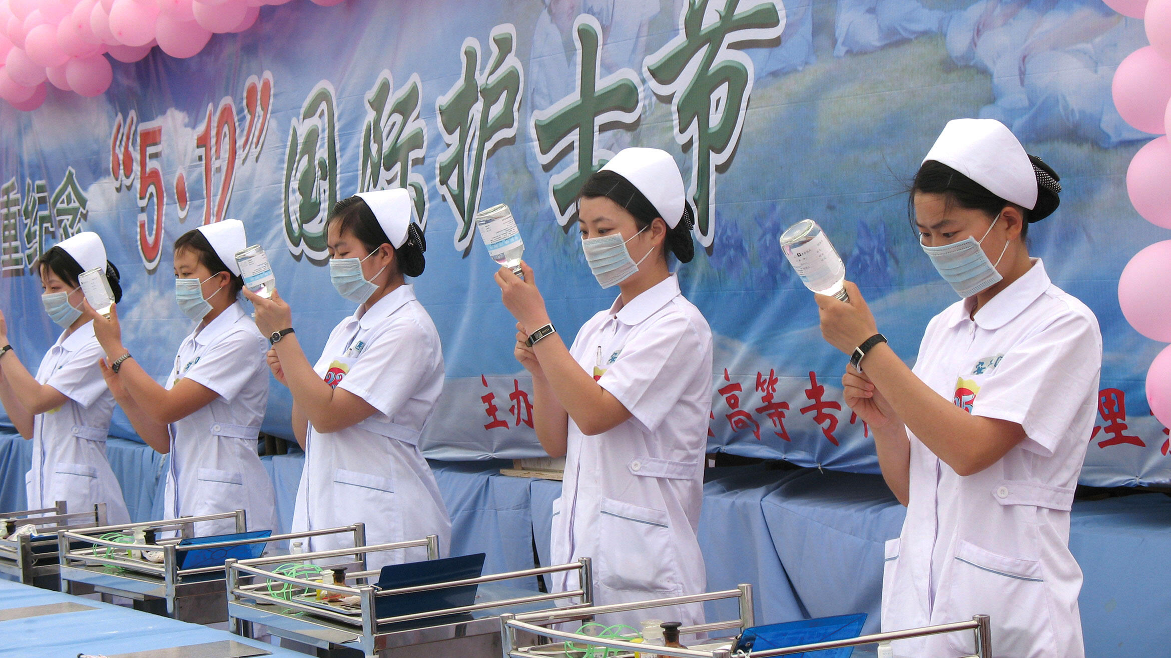 Chinese women in white coats stand in a row and draw syringes