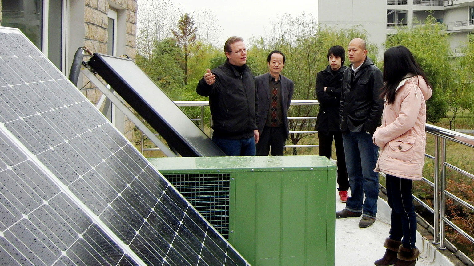 some people from China stand around solar cells and follow the explanations of a German