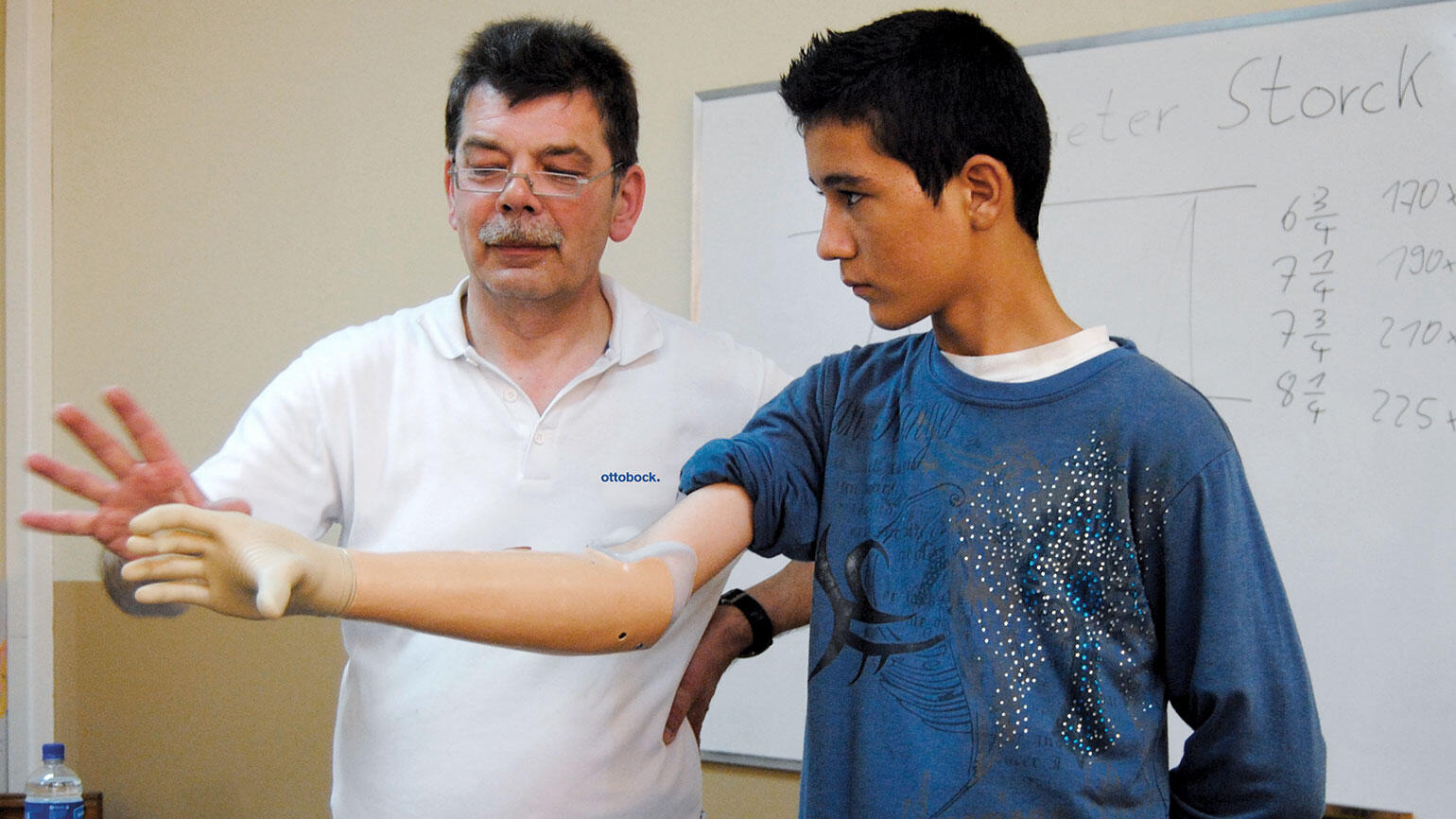 young man practices the use of his artificial arm with a coach