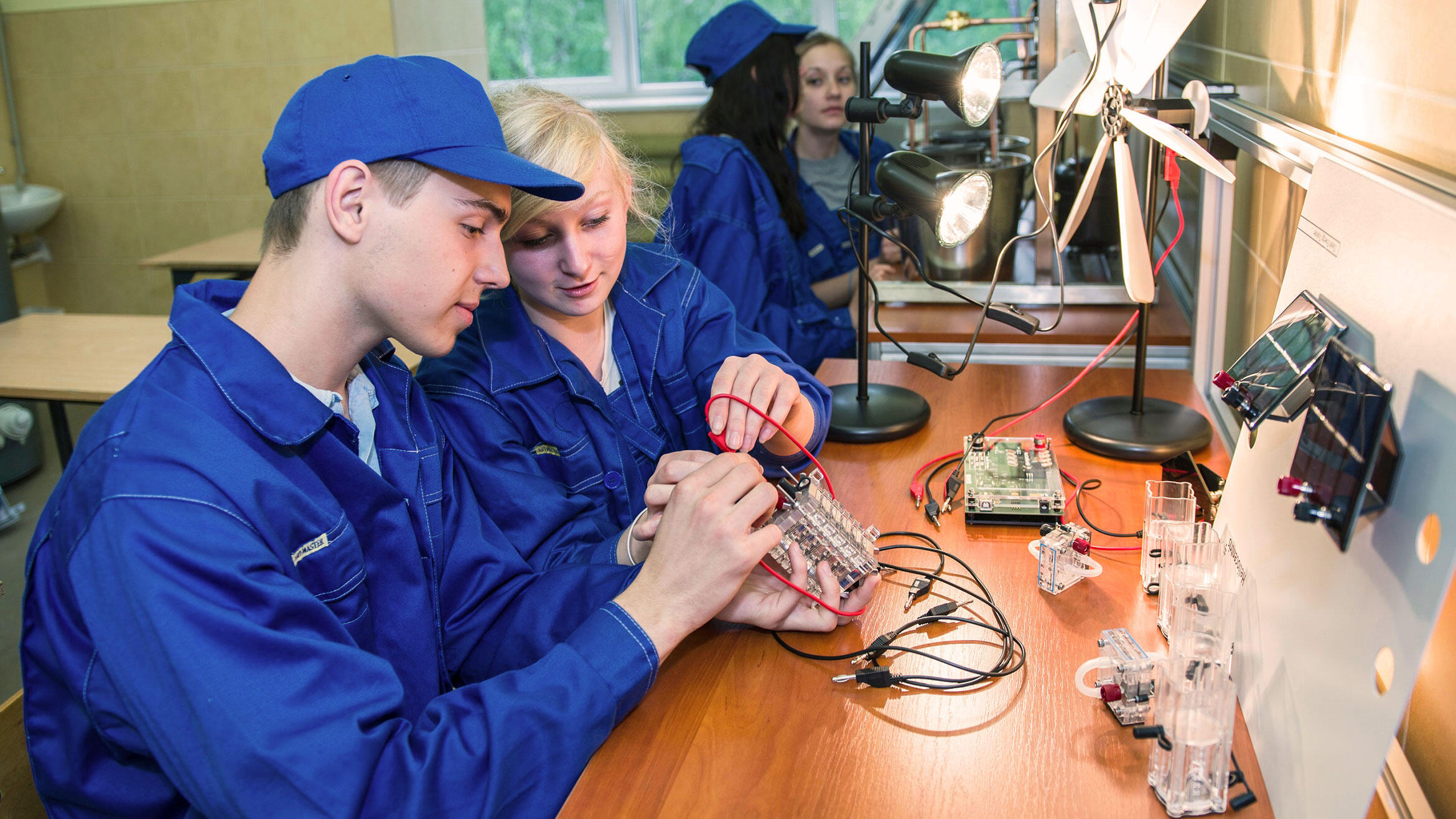 young man and woman from Poland practice electronic work in a teaching workshop