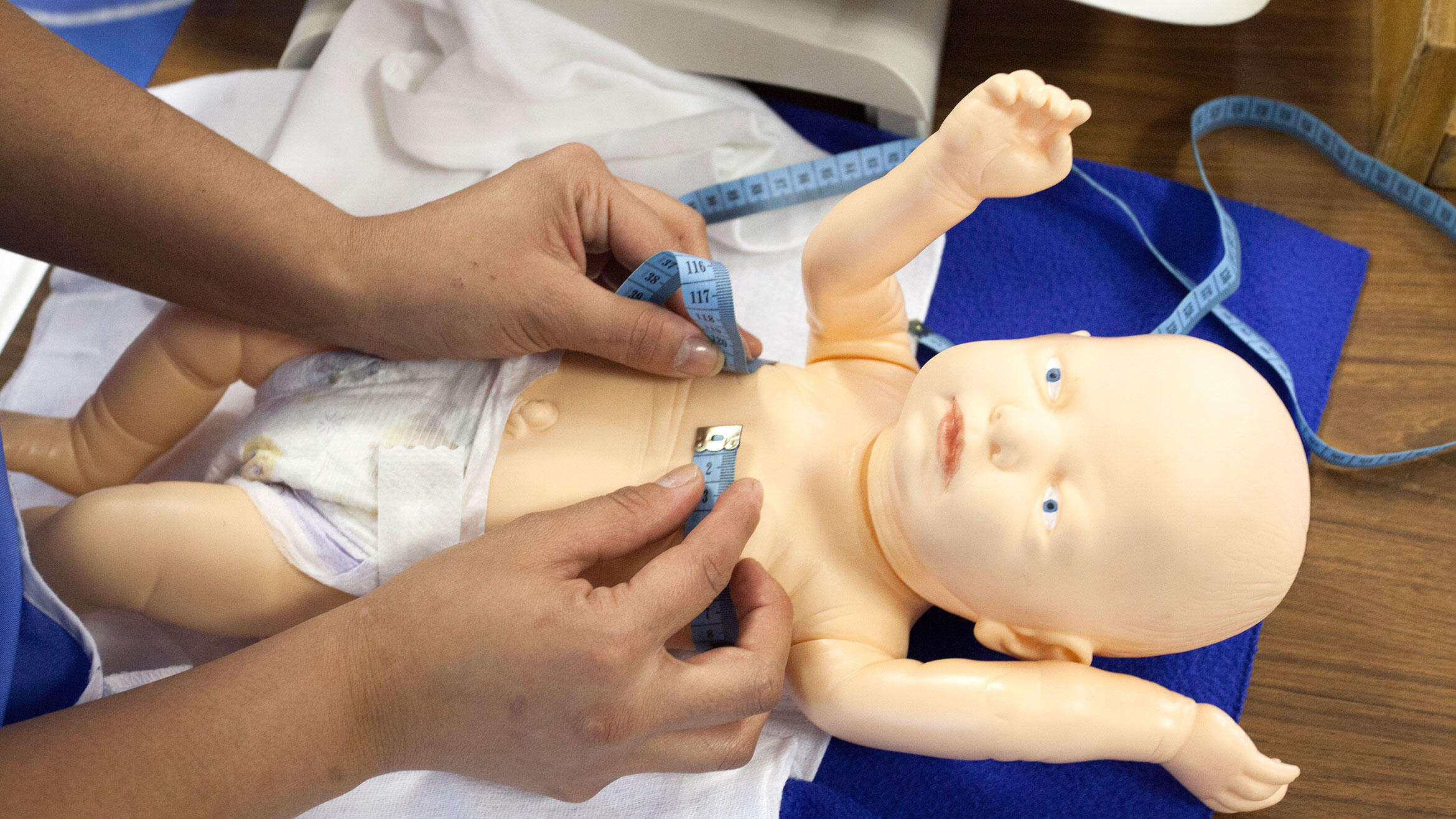 someone measures the chest circumference on a baby doll