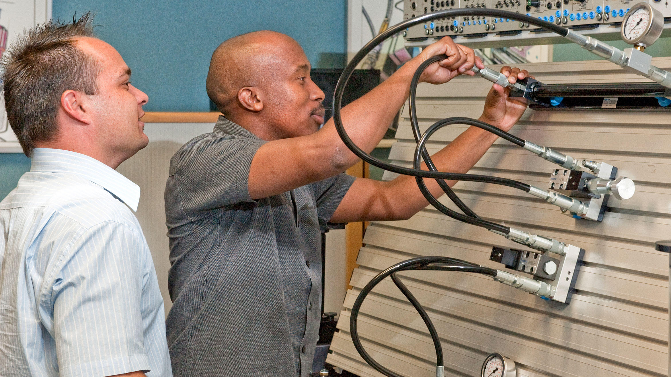 two men connect hoses to a training facility