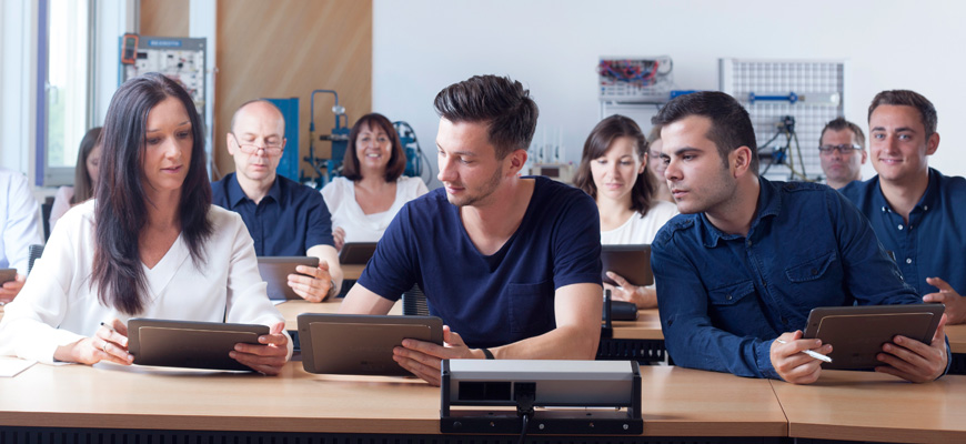 trainees sitting in a classroom and looking at their tablets