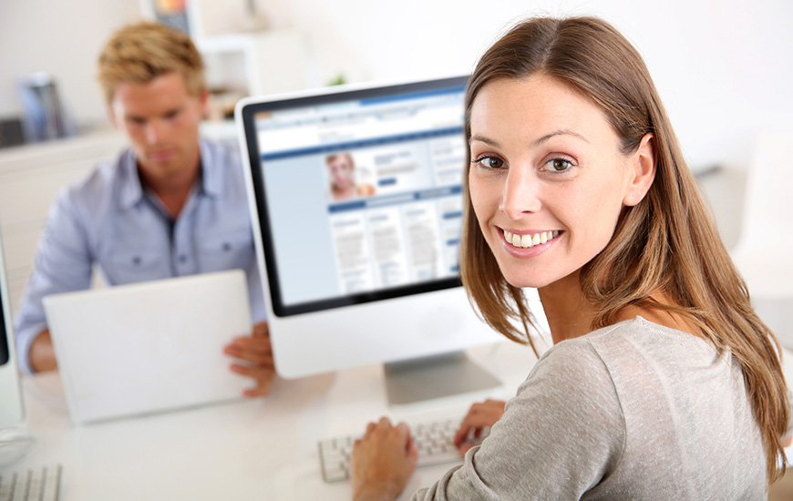 woman works at a computer and smiles at the camera