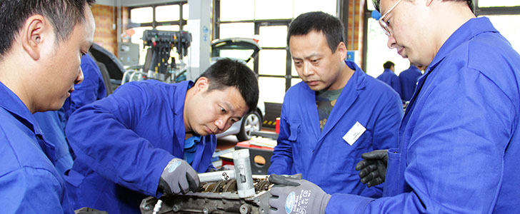 several Chinese trainees working on an automotive machine