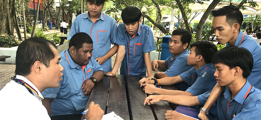 Several Thai men sit around a table and talk to eachother