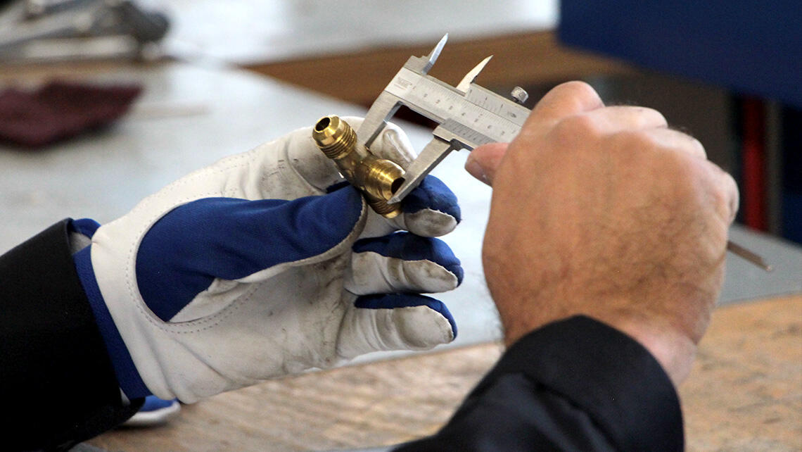 detailed view: hands measure length of a valve