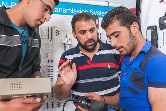 three Arab trainees and a trainer working in a technical area