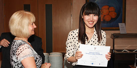 young woman smiling and holding her European Wine Certificate 