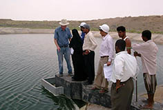 several people standing at the border of a freshwater lake in a dry area
