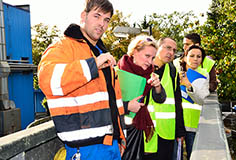 several women and men in safety jackets looking at something outside