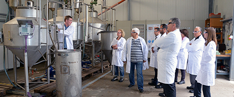 German instructor showing a water filter system to a group of people in white work coats