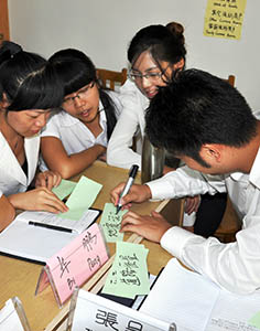 Close-up of several young Chinese writing on notecards