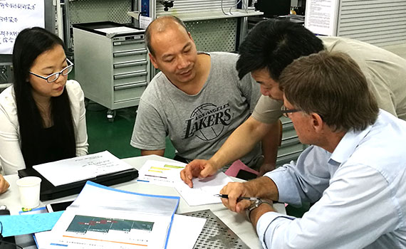 several chinese people sitting around a table and working together