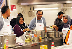 Malaysian women and men cooking in a canteen kitchen