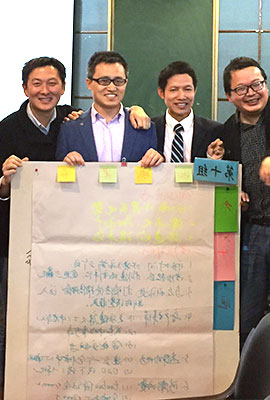 four Chinese men holding a chart showing results 
