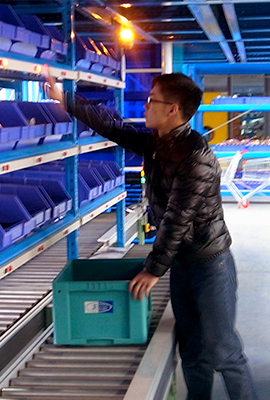 Chinese stands in front of a shelf with crates