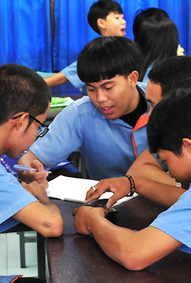 young Thai siting at a table and examining a something