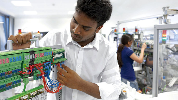 man from Southeast Asia in a workshop working in the area of eletronic