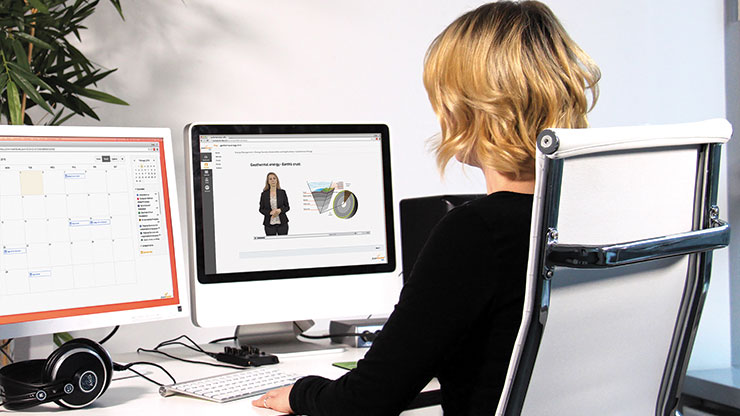 Women sitting at a table looking at two monitors