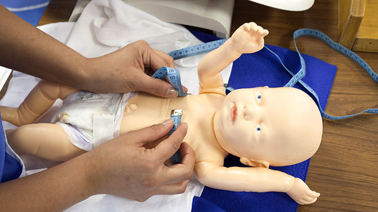 someone measures the chest circumference on a baby doll