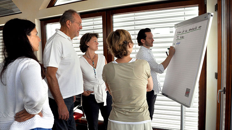 people standing around a flipchart, one person ist writing on it